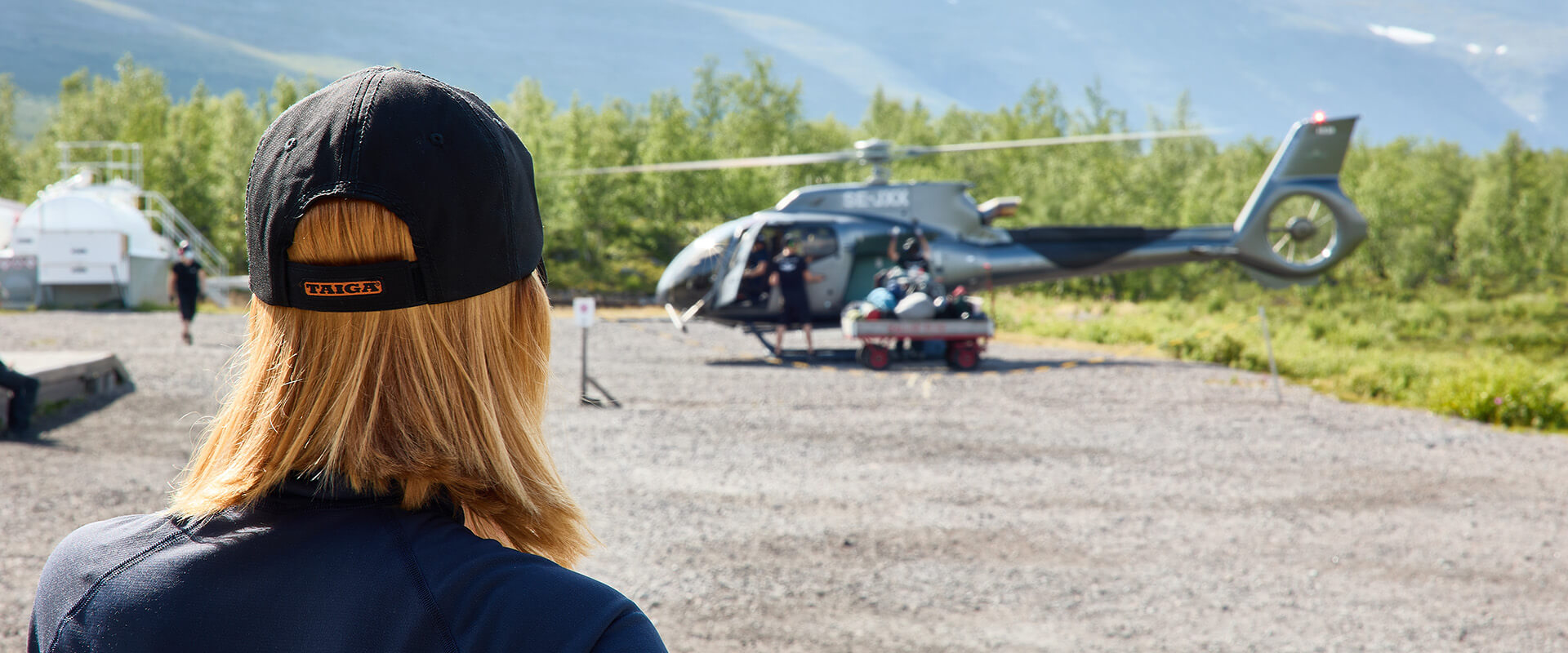 Woman wearing a Taiga cap next to a helicopter